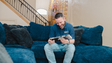 adam looking at VHS tape sitting on a couch