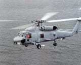 left side view of military helicopter in flight over water