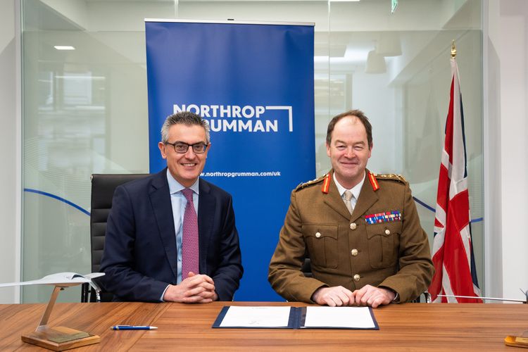 Two men smiling behind an office desk. 