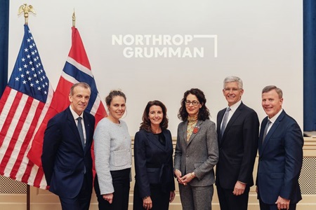 six people standing posed in front of Norway and USA flag.