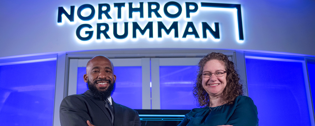 man and woman in front of Northrop Grumman sign