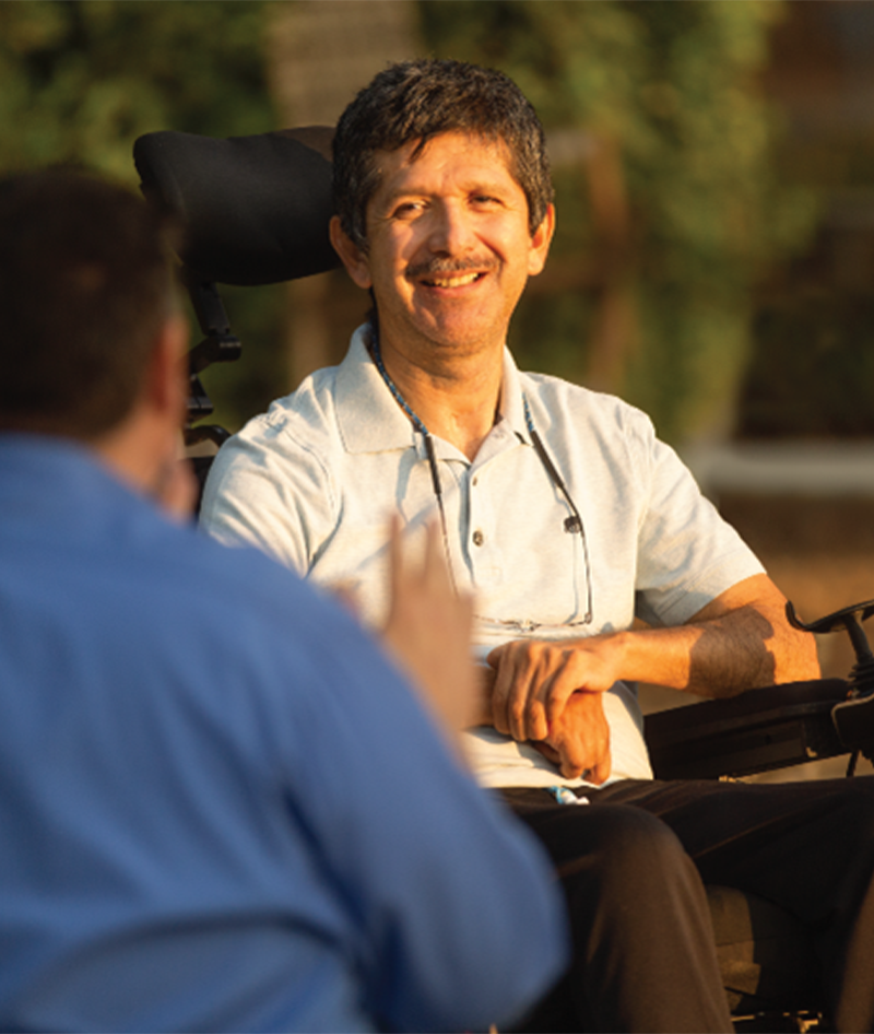 man in white shirt sitting talking to man in blue shirt sitting