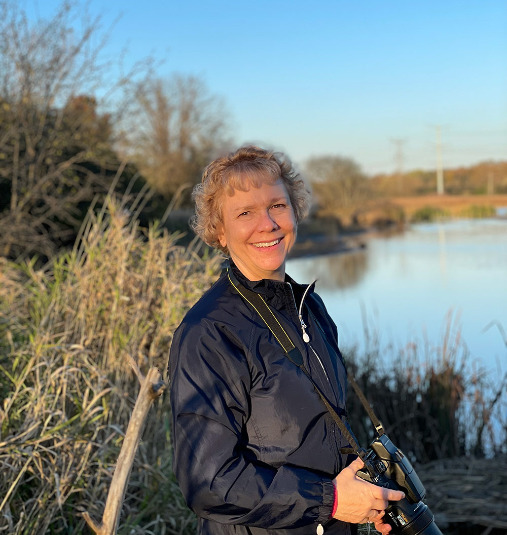 woman with camera in hand next to lake