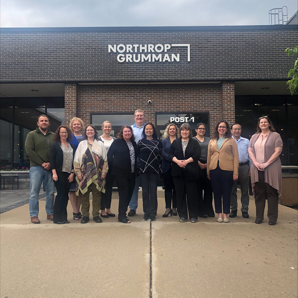 group of employees stand in front of Northrop Grumman building