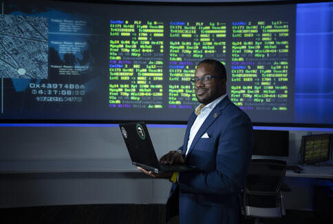 man holding a laptop in front of a screen