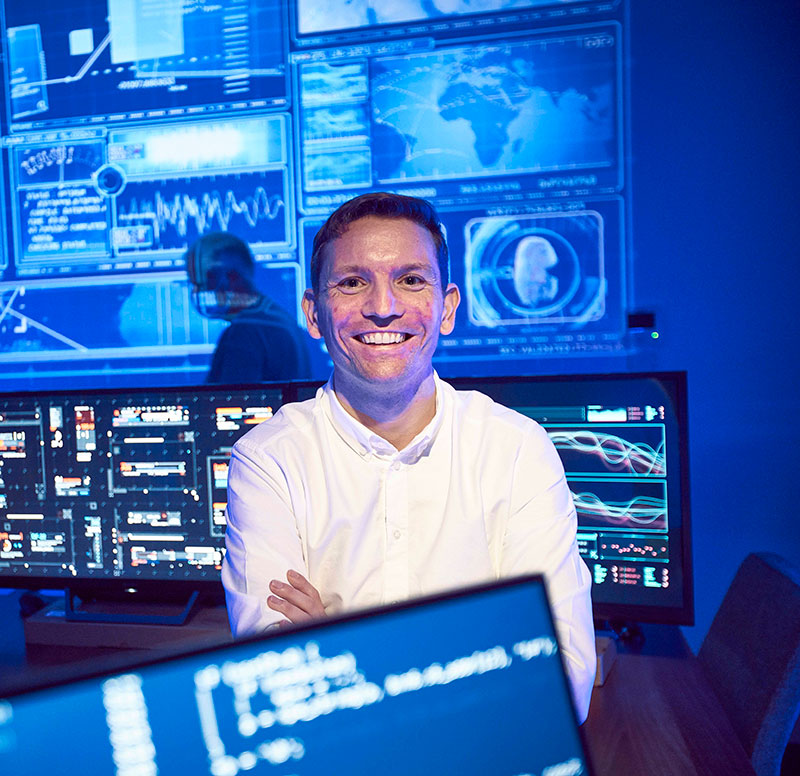 smiling man in white shirt and arms folder in situation room
