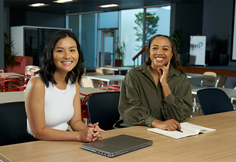 two people sitting at a desk smiling
