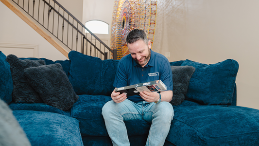 adam looking at VHS tape sitting on a couch