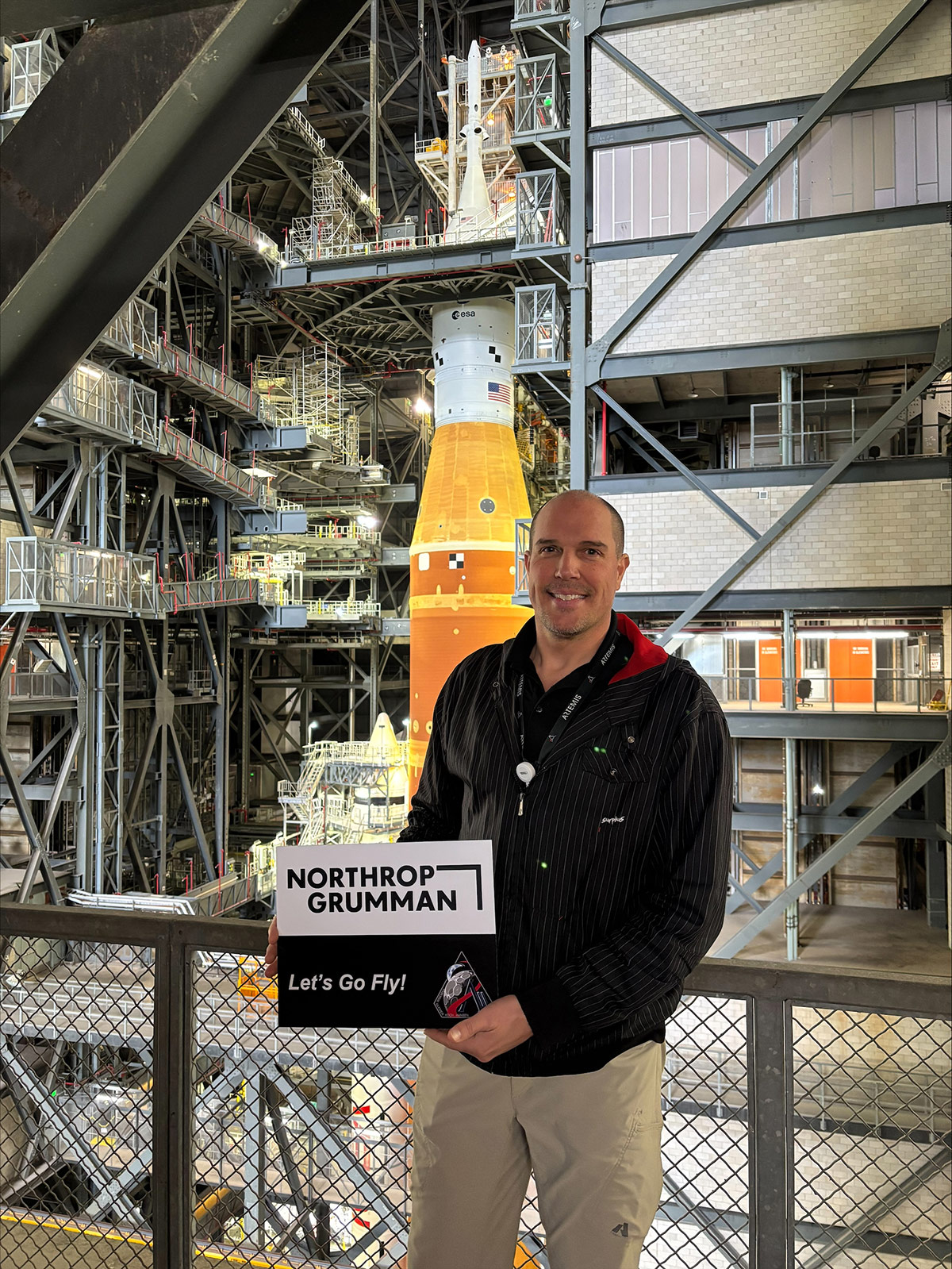 man holding sign in front of Artemis II rocket