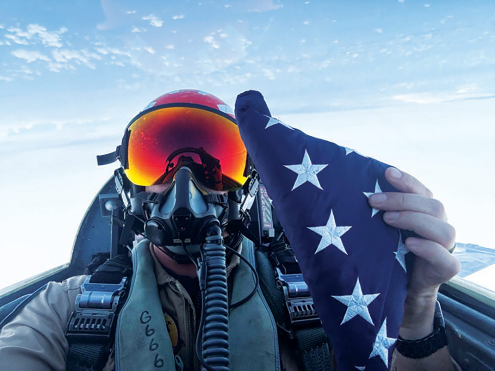 Pilot in fighter jet holds U.S. flag