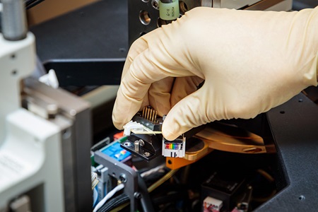 gloved hand handling microchip in lab