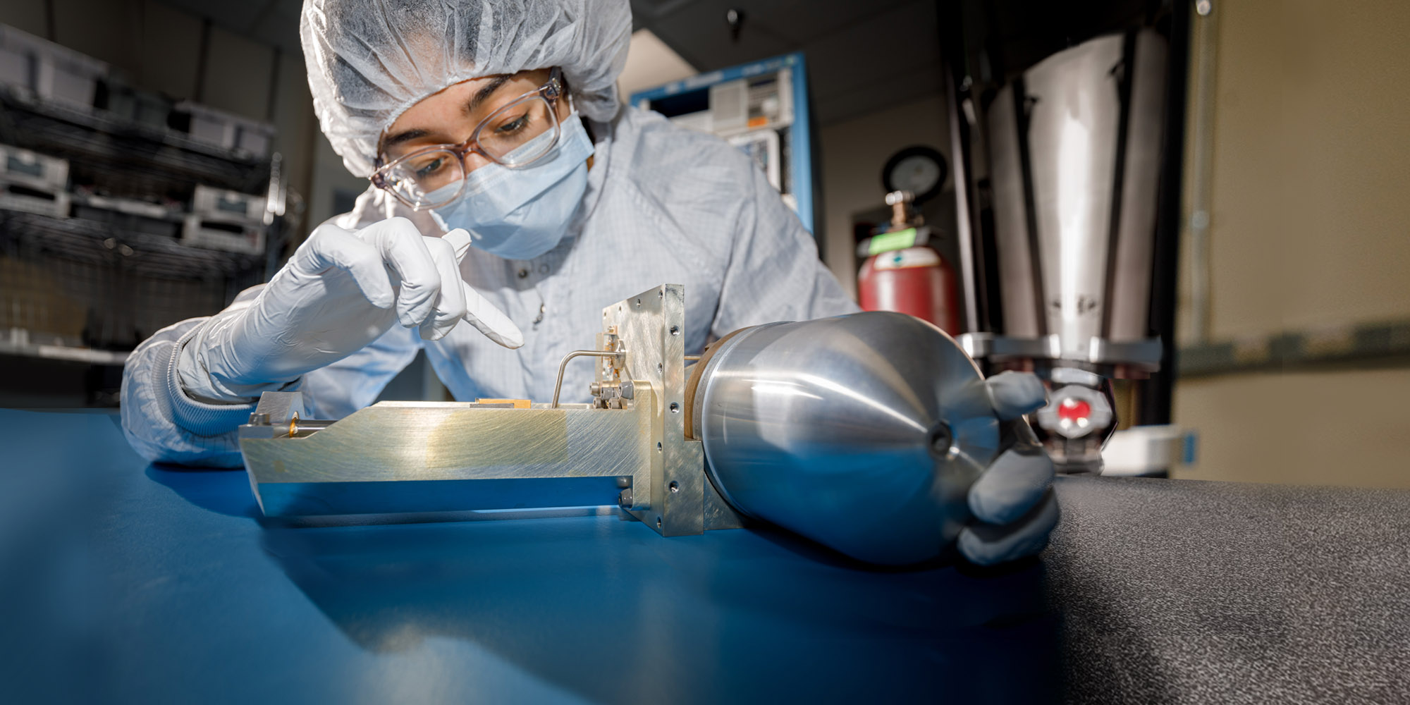 technician in bunny suit working on space part