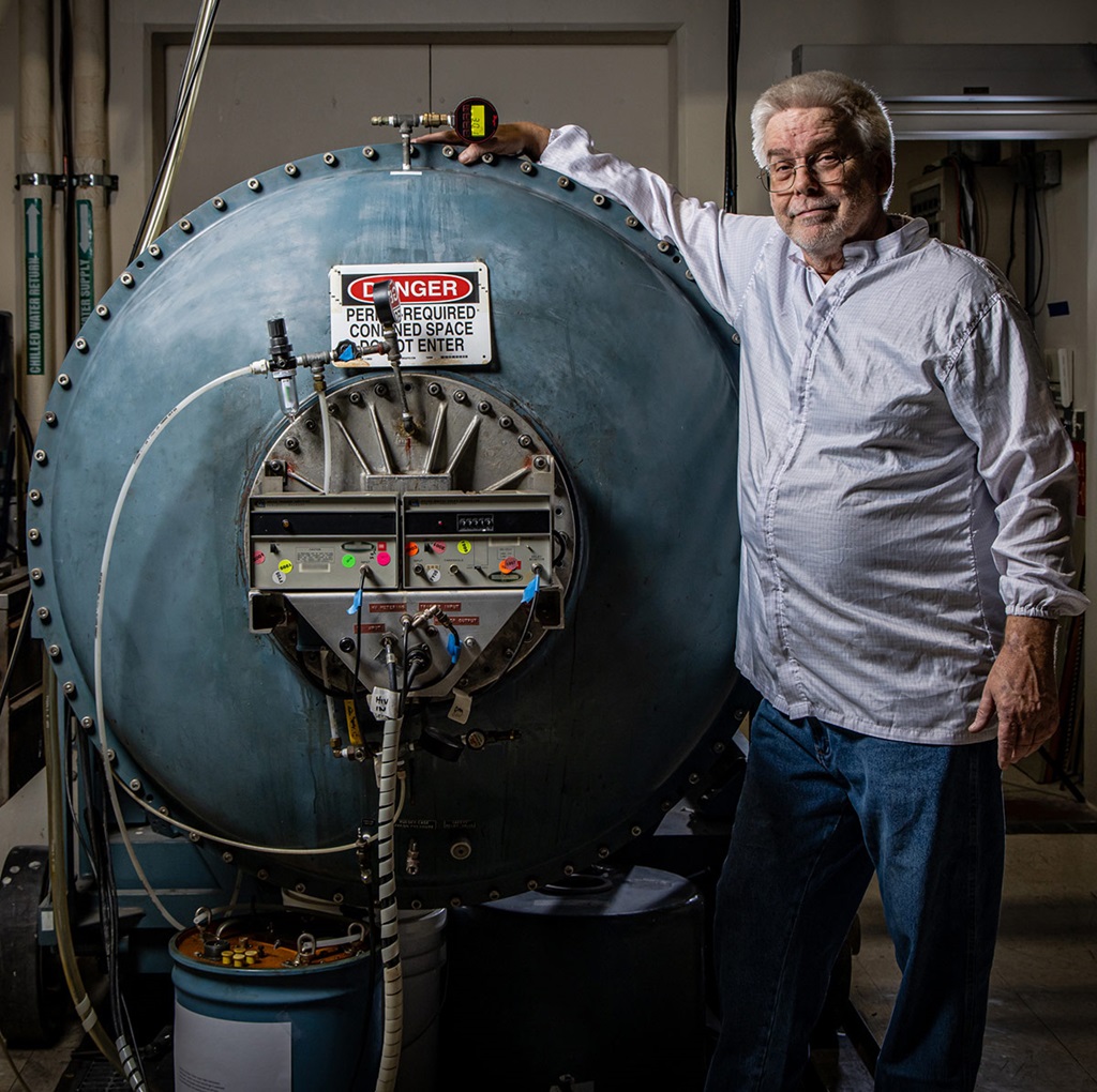 man in lab coat touching large tank