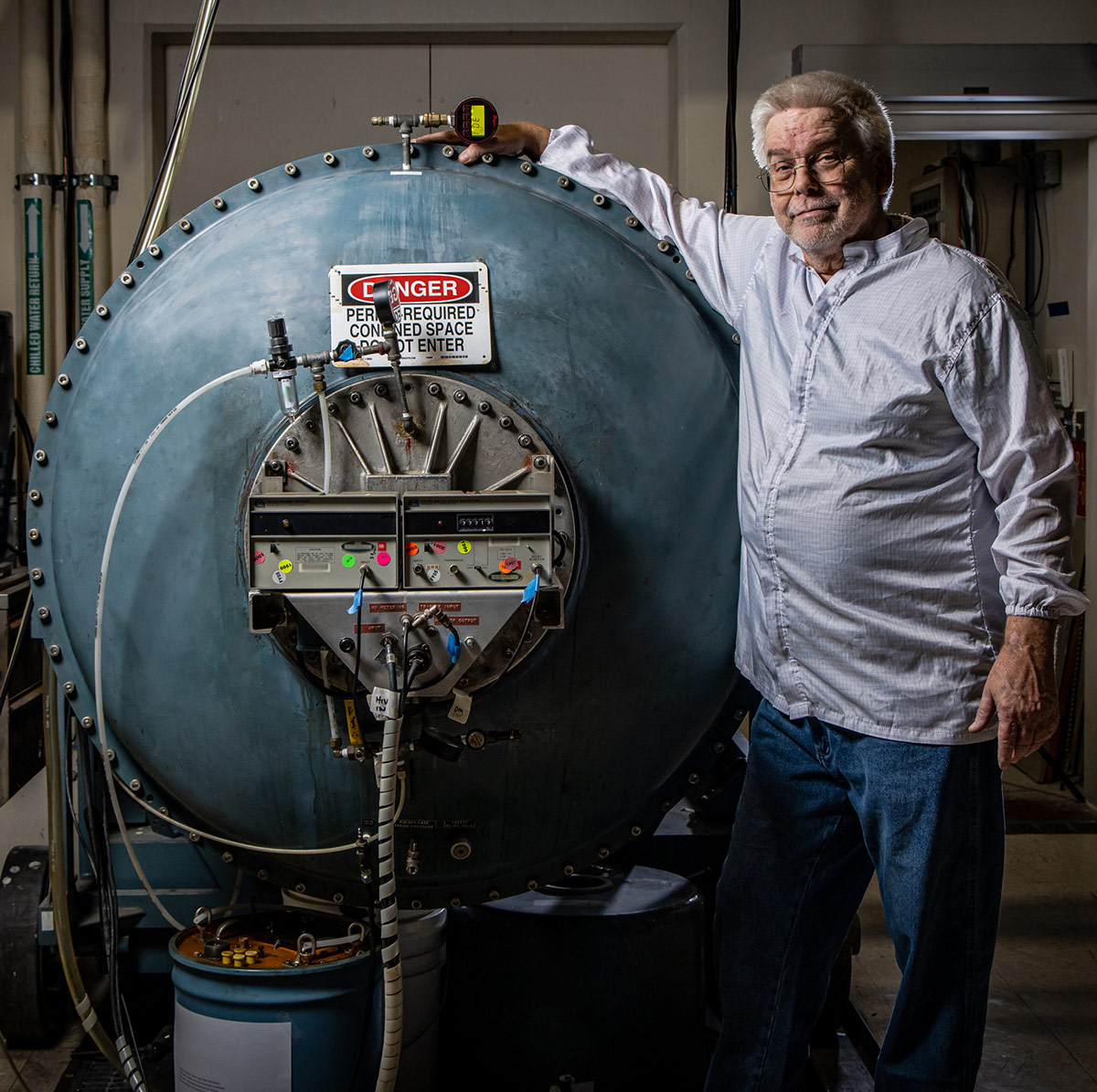 man in lab coat touching large tank