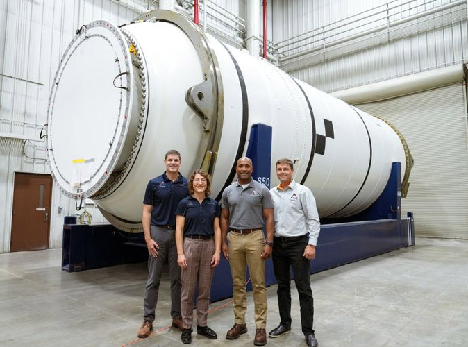 four people standing in front of rocket