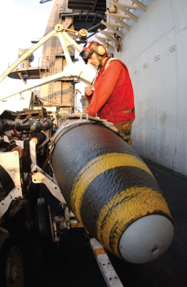 US Military personnel loading a bomb on a ship