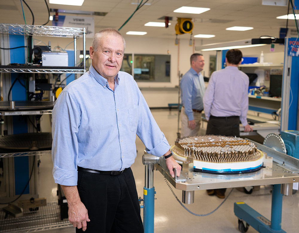 employee standing next to active electronically scanned array radar in lab