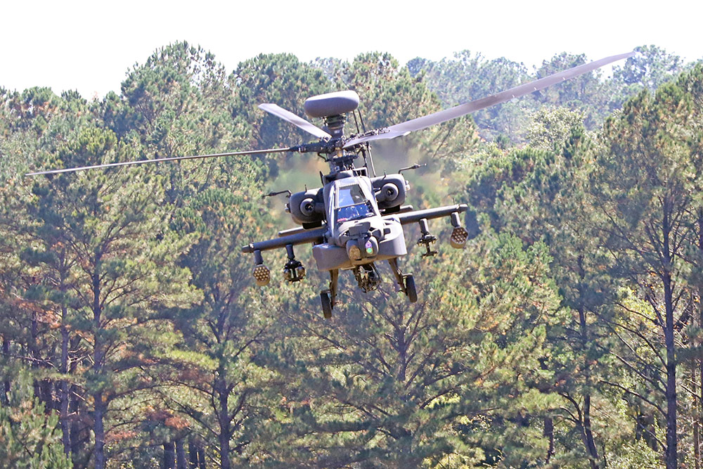apache helicopter flying above trees