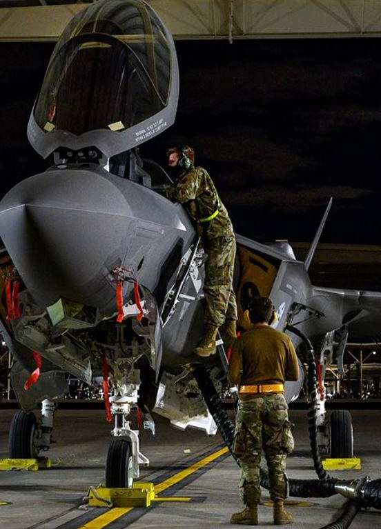 two military personnel working on a fighter jet