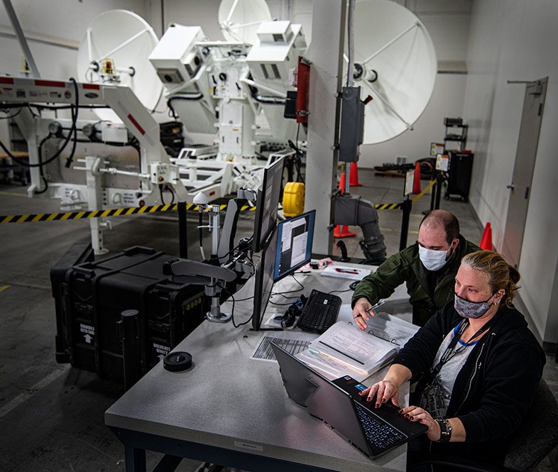 two people working on laptop next to radar