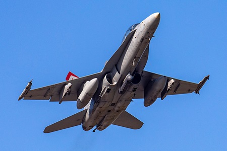 military jet ascending in flight in blue sky
