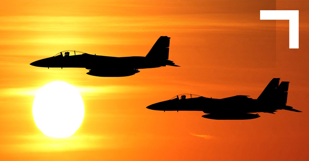 silhouette of two military jets in red sky