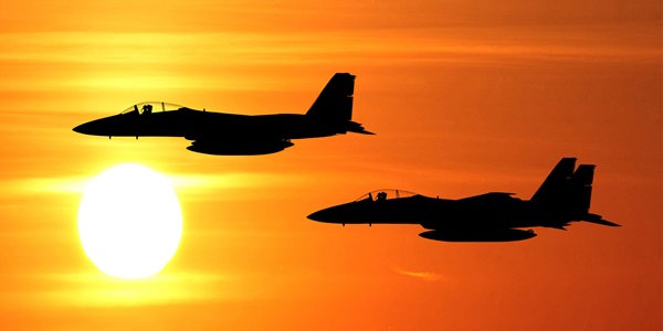 silhouette of two military jets in red sky