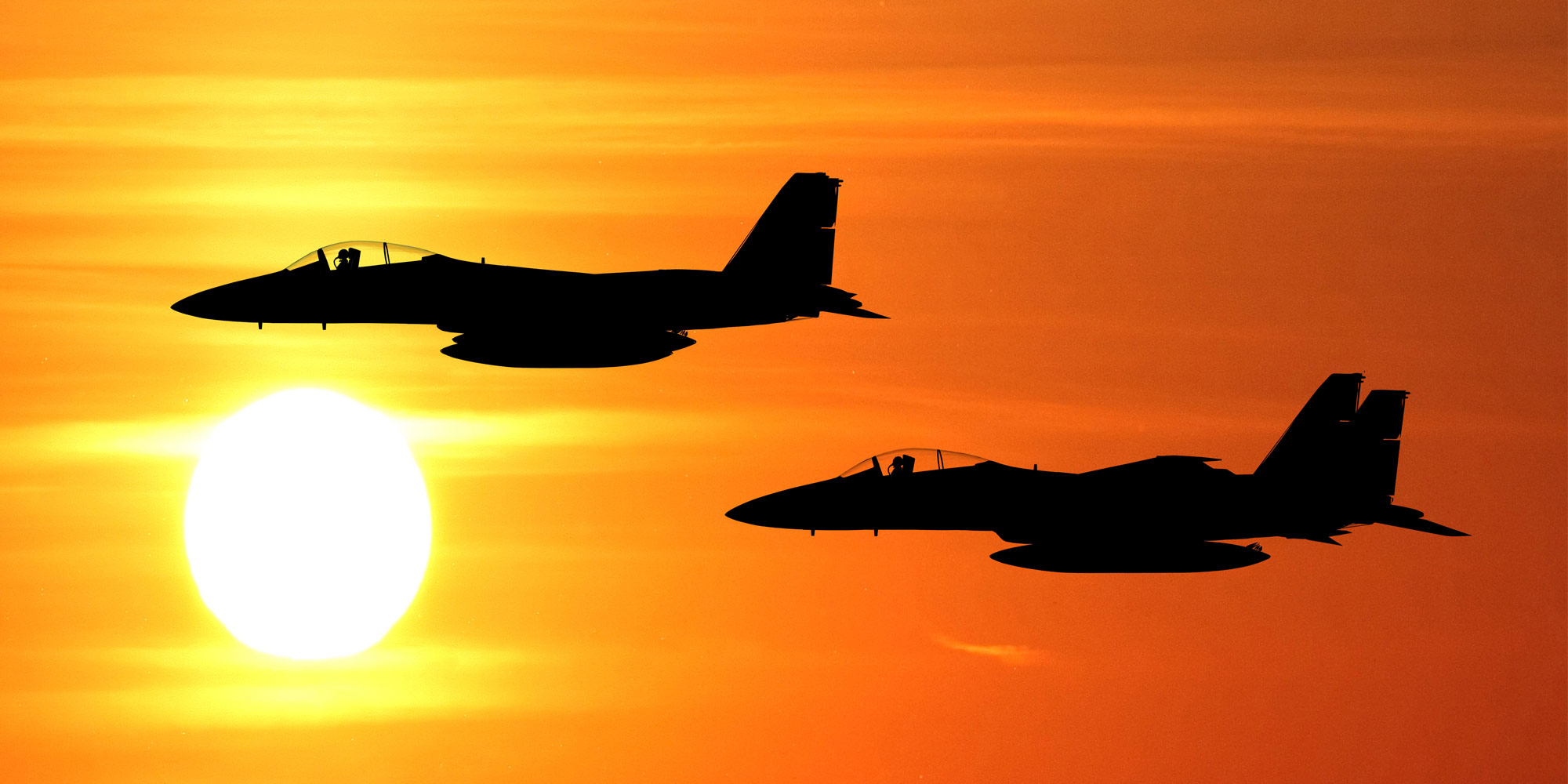 silhouette of two military jets in red sky
