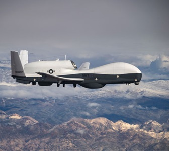 photo of military triton aircraft in flight above mountains. 