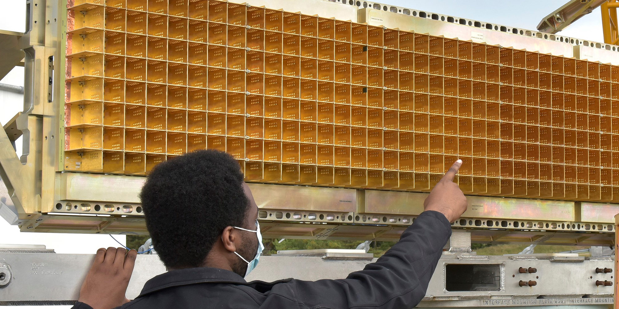 A man wearing a Northrop Grumman jacket points to a sensor panel