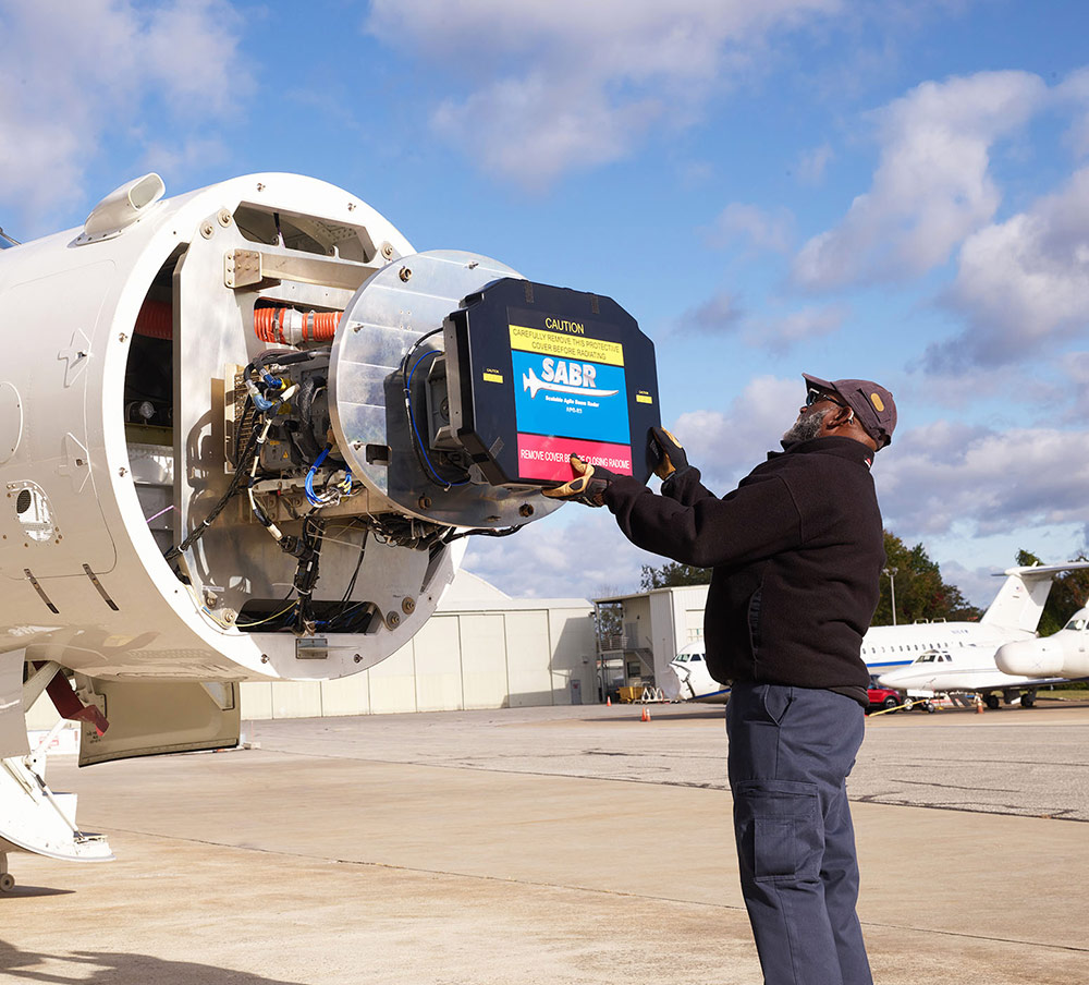 employee installing radar to nose of aircraft