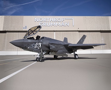 fighter jet on tarmac in front of hangar