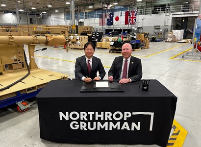 two males sitting at a table in manufacturing bay