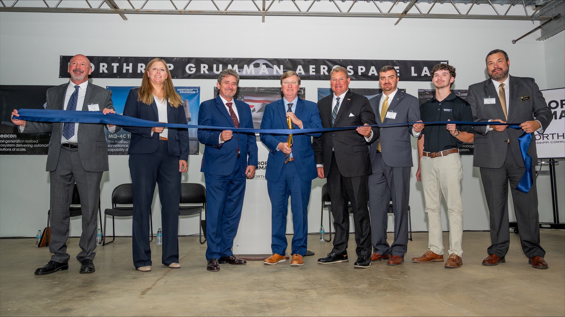 Eight people in suits at ribbon cutting ceremony