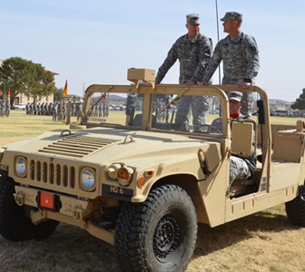 two men standing in military jeep with a driver