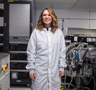 lab technician standing next to metal deposition tool