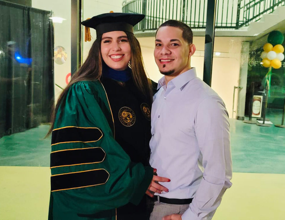 Sabrina defended her thesis at University of South Florida (USF) while nine months pregnant. women wearing collage graduation robe standing next to man