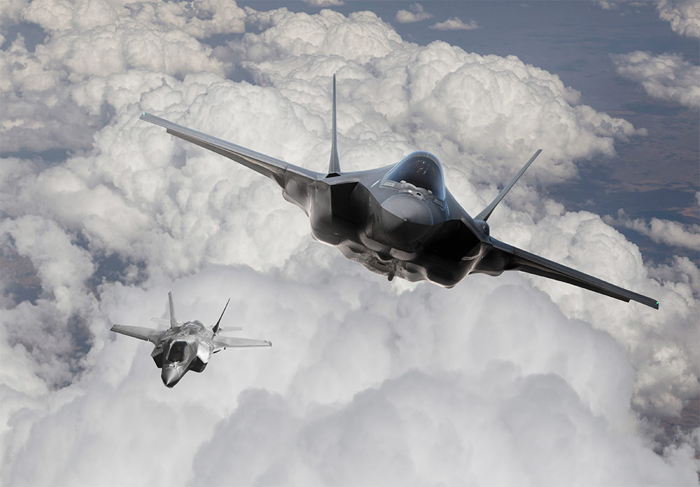 Combat Electromagnetic Environment Simulator (CEESIM) Two advanced fighter jets flying through a cloud-filled sky, showcasing Northrop Grumman's cutting-edge technology in electronic warfare simulation.