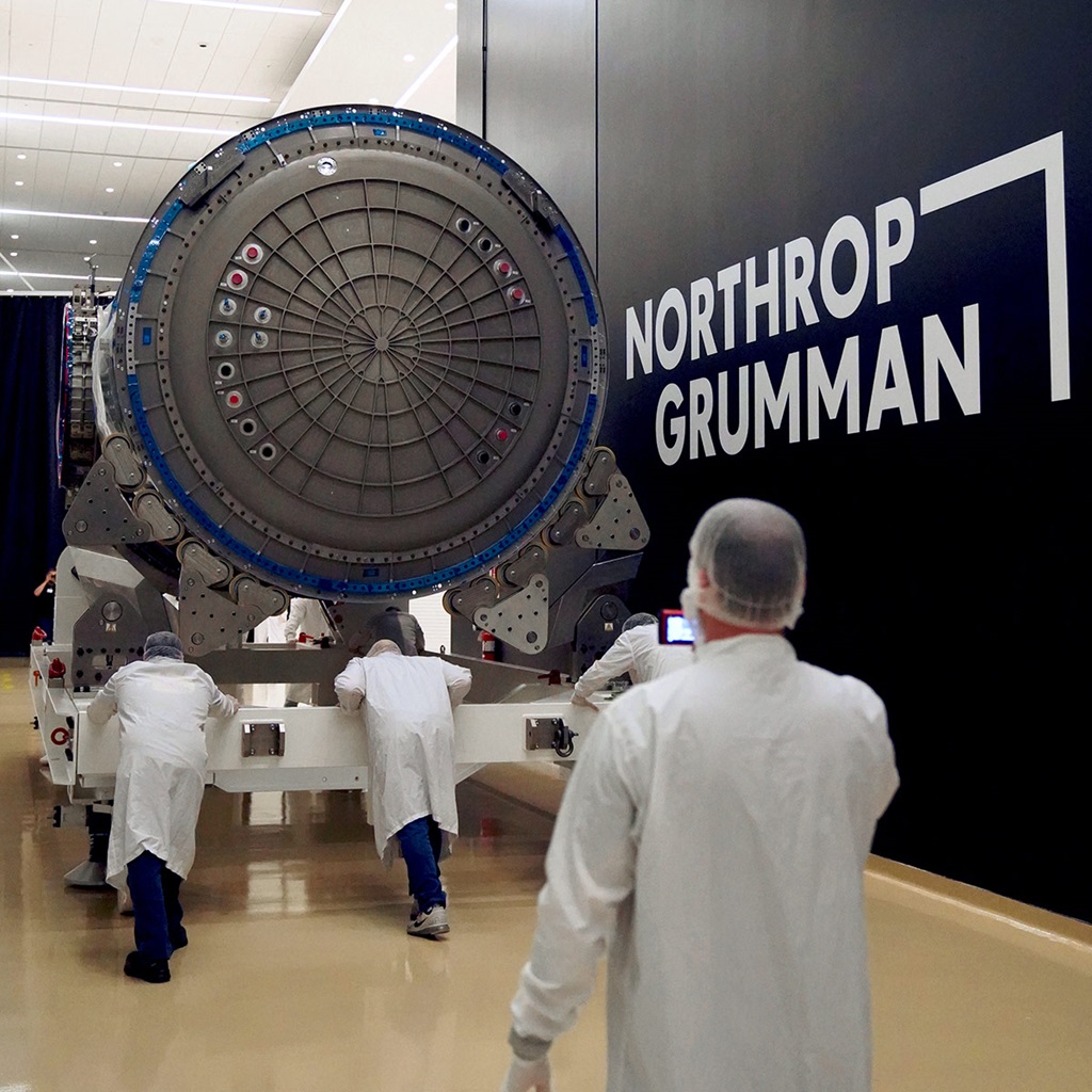 Workers in white lab coats pushing HALO in NGC facility