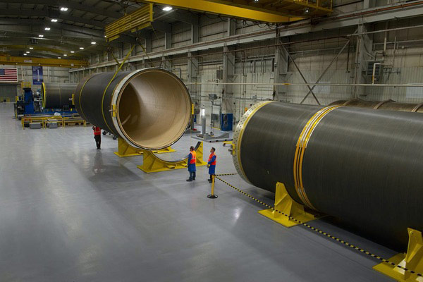 workers with rocket booster sections in facility