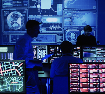 Image of computers and displays lit up in dark room