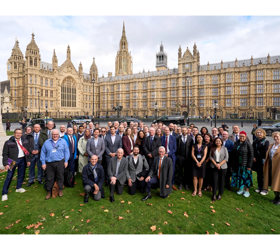 large group of people on lawn outside gothic architecture on college campus