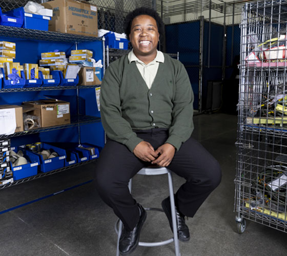 student sitting on bar stool in front of equipment smiling
