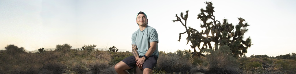 male seated in desert.