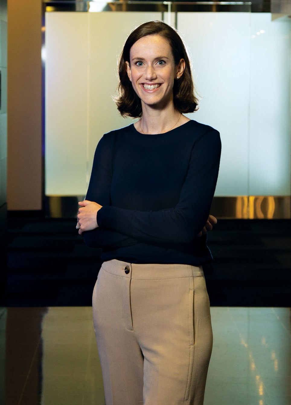 Woman standing and smiling with arms crossed. 