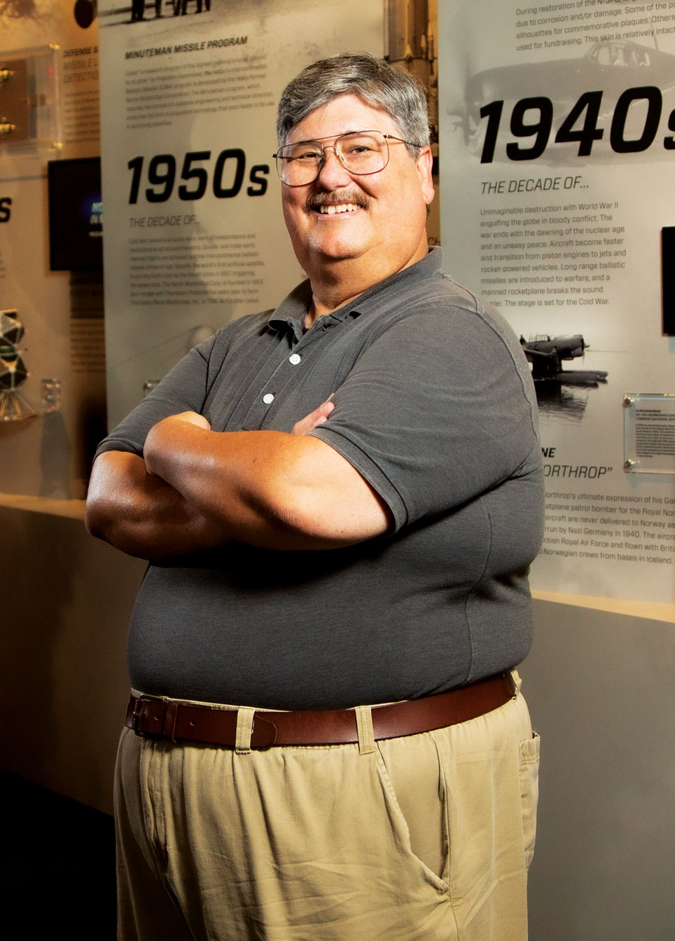 Man smiling with arms crossed looking at viewer.