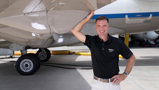 man standing under aircraft wing smiling