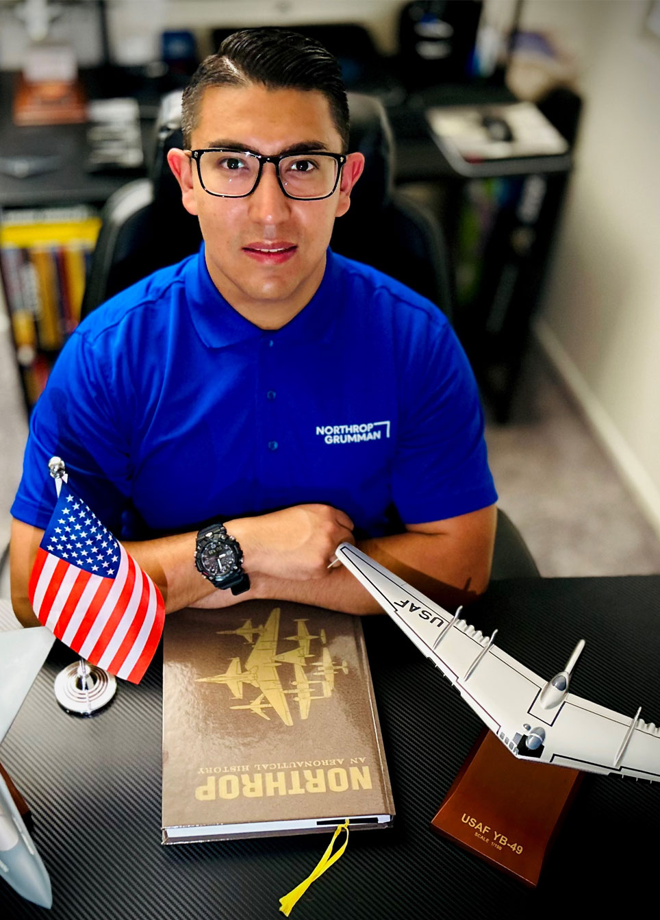 Diego sits at a table with model planes, a Northrop History book and an American flag.