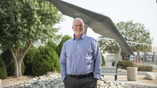 Man standing near bridge outdoors smiling. 