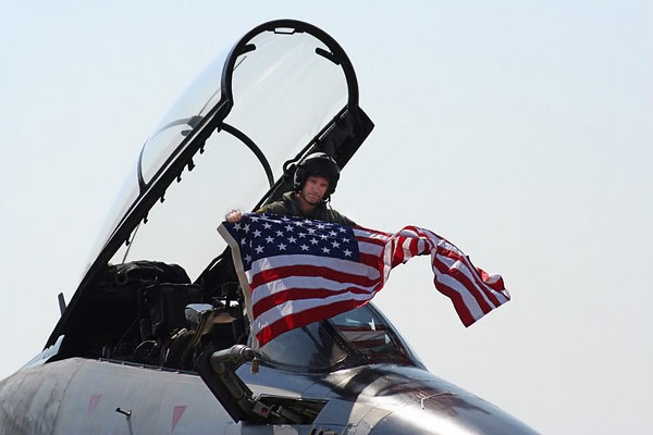 pilot displays american flag outside cockpit of jet aircraft. 